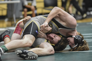 Chayce Collier in gold and black wrestles another high school wrestler.